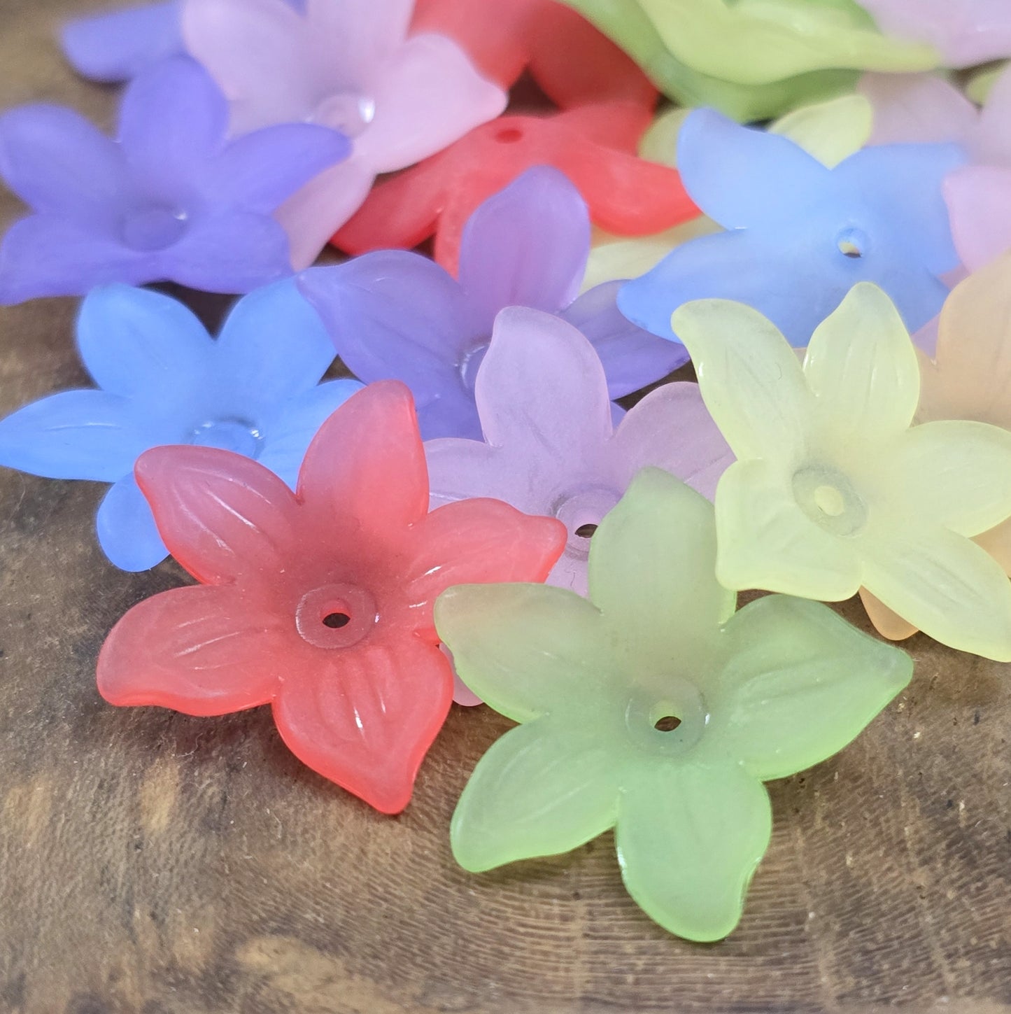 50 Blumenperlen im bunten Farbmix, jede mit einem Durchmesser von 2,2 cm. Die Perlen zeichnen sich durch ihre matte Oberfläche aus und präsentieren sich im stilvollen Sternblüten-Design. Mit dem praktischen Loch zum Auffädeln sind sie ideal für eine Vielzahl kreativer Projekte.