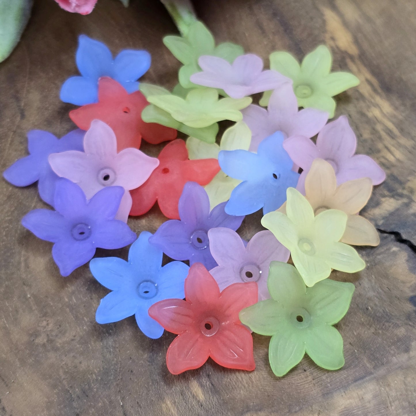 50 Blumenperlen im bunten Farbmix, jede mit einem Durchmesser von 2,2 cm. Die Perlen zeichnen sich durch ihre matte Oberfläche aus und präsentieren sich im stilvollen Sternblüten-Design. Mit dem praktischen Loch zum Auffädeln sind sie ideal für eine Vielzahl kreativer Projekte.