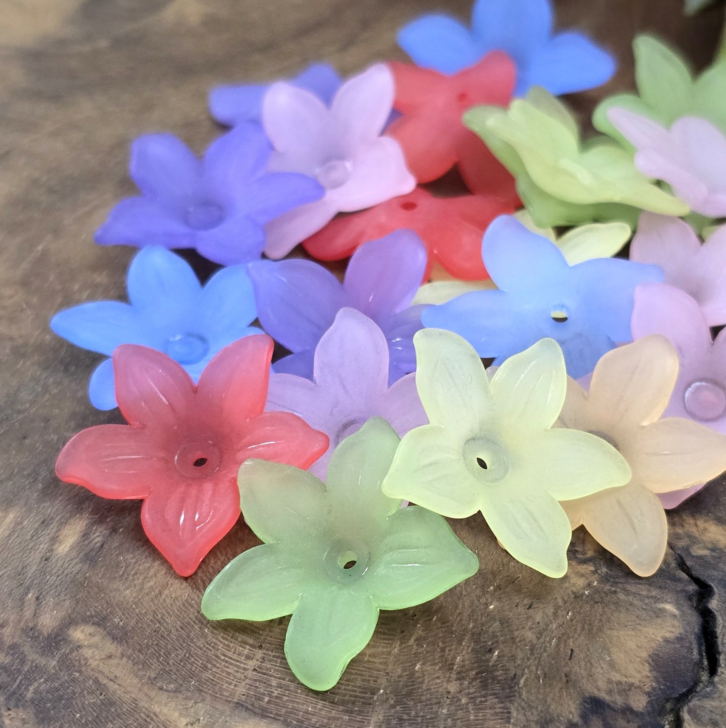 50 Blumenperlen im bunten Farbmix, jede mit einem Durchmesser von 2,2 cm. Die Perlen zeichnen sich durch ihre matte Oberfläche aus und präsentieren sich im stilvollen Sternblüten-Design. Mit dem praktischen Loch zum Auffädeln sind sie ideal für eine Vielzahl kreativer Projekte.