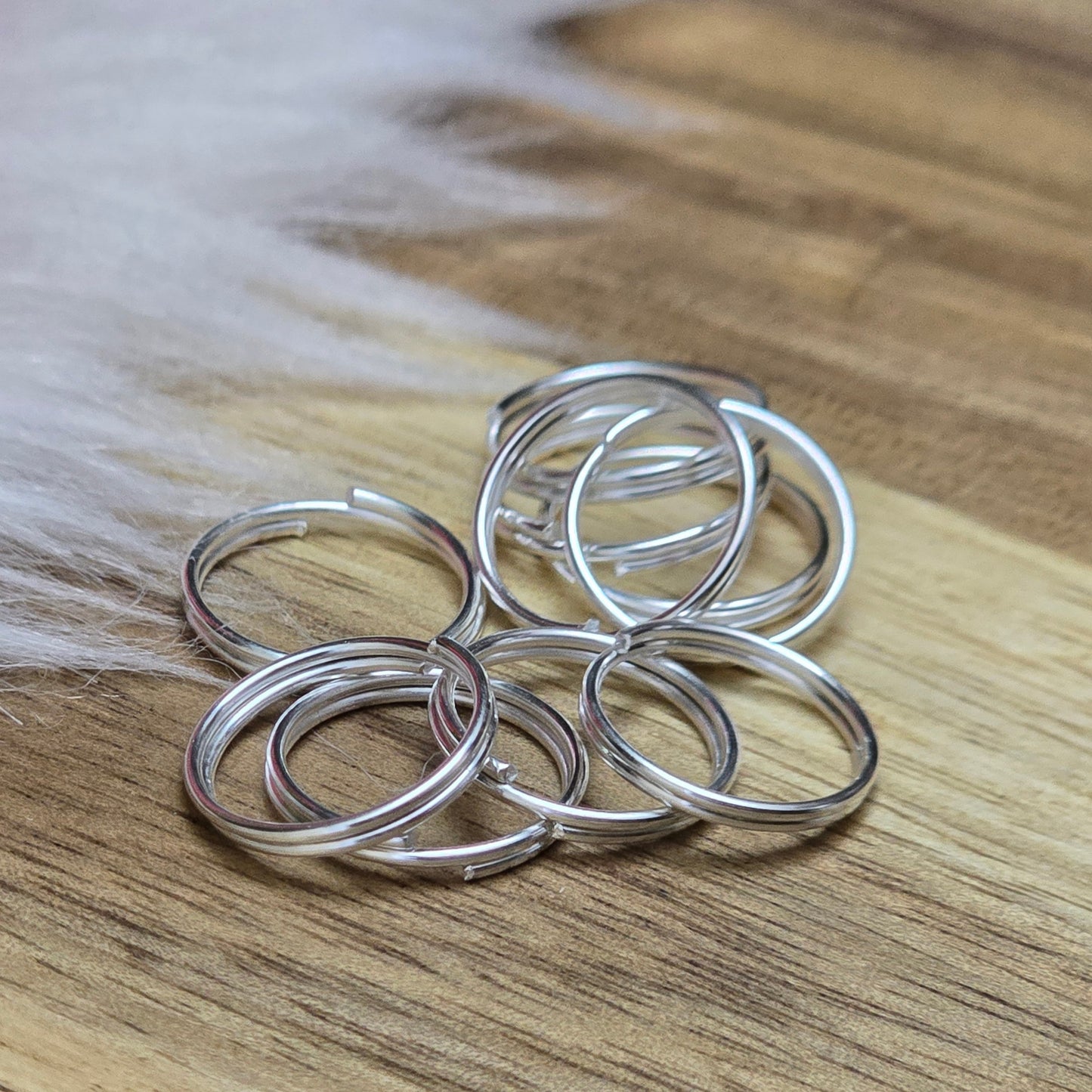 Das Bild zeigt 10 doppelte Binderinge in versilbert mit einem Durchmesser von 12mm. Die Verbindungsringe sind ein unverzichtbares Zubehör für die Schmuckherstellung. Durch ihre doppelte Wicklung bieten sie eine besonders stabile und sichere Verbindung, sodass Anhänger, Charms und Verschlüsse zuverlässig befestigt bleiben.