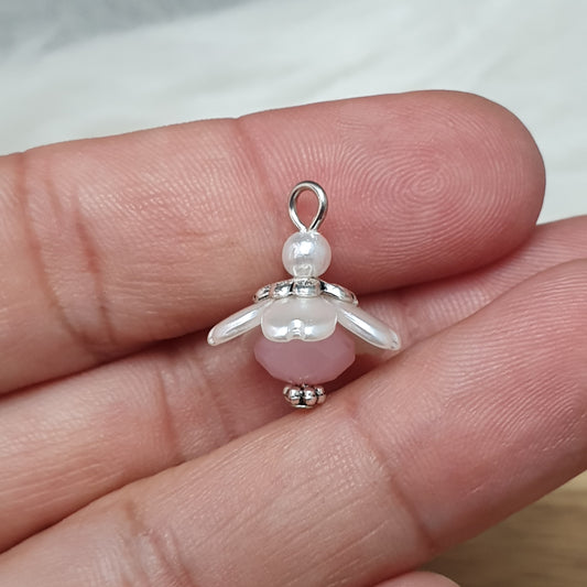 Auf dem Bild sind zwei handgefertigte Anhänger in Form von kleinen Blumen zu sehen. Die Anhänger bestehen aus einer eleganten weißen Acrylblüte und einer zarten rosafarbenen Kristallglasperle. Silberfarbige Metallelemente runden das Design ab und verleihen den Anhängern einen romantischen Charme. Mit einer Größe von ca. 18mm sind sie ideal für die individuelle Schmuckgestaltung, sei es für Ketten, Armbänder oder Ohrringe.