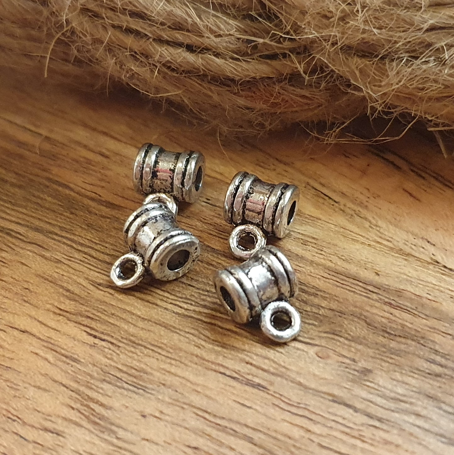 Sie erhalten hier 4 Ösenperlen in schlichtem Ethno-Design und einem tollem antik silbernem Finish. Die Perlen sind länglich gearbeitet und haben eine kleine Öse. Man kann sie z.B. in ein Armband oder Kette einarbeiten und einen kleinen Anhänger anbringen. Die Mitte der länglichen Form kann noch verziert werden mit Strass, Stoff oder Farbe. Das Band sollte nicht dicker als 3mm sein. Ideal auch für Makramee oder zum Einarbeiten in Makramee-Dreads und Hairwraps.