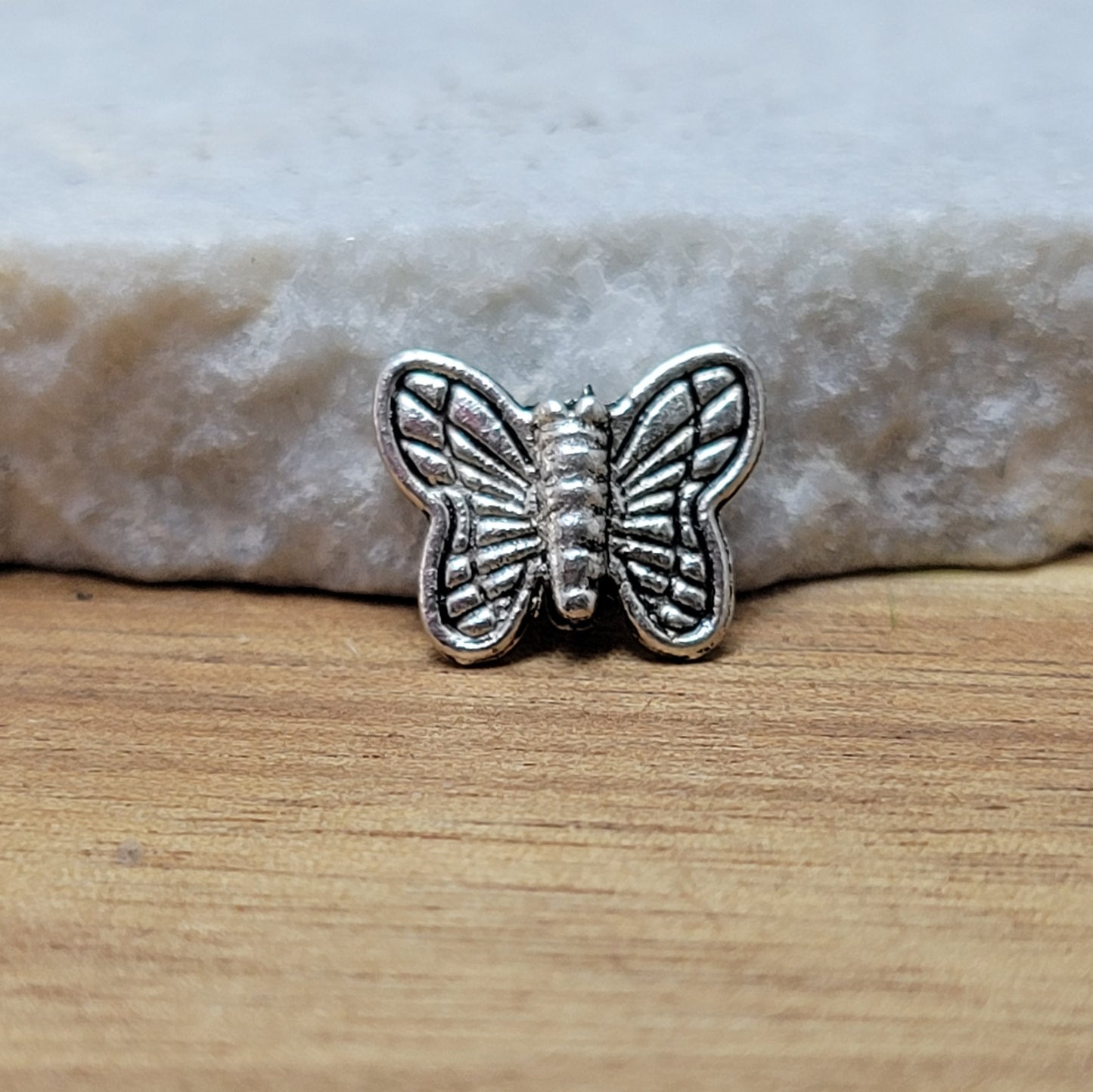 Eine Packung mit 5 Metallperlen in Form eines Schmetterlings. Die Perlen sind beidseitig geprägt, antik silberfarbig und haben eine hübsches Antikfinish, was für einen tollen Vintage-Effekt sorgt. Das Fädelloch verläuft von oben nach unten durch den Schmetterling.