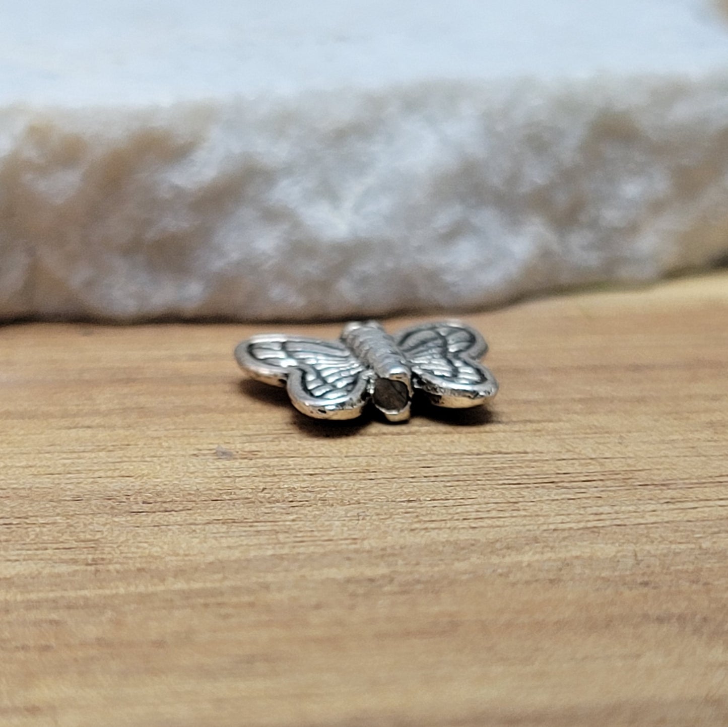 Eine Packung mit 5 Metallperlen in Form eines Schmetterlings. Die Perlen sind beidseitig geprägt, antik silberfarbig und haben eine hübsches Antikfinish, was für einen tollen Vintage-Effekt sorgt. Das Fädelloch verläuft von oben nach unten durch den Schmetterling.