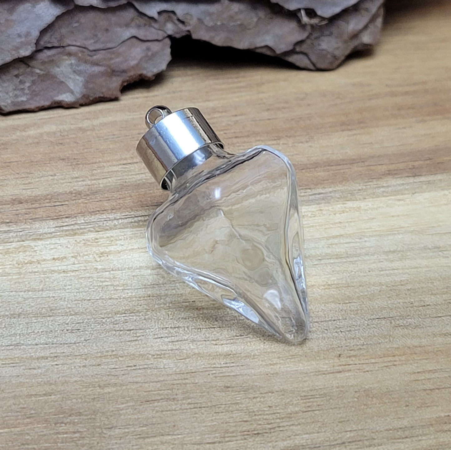 Anhänger Glasflasche in konischer Form, ideal zum befüllen. Die Glasflasche hat eine nach unten spitz zulaufende Form mit sechs flachen Seiten und einer Öffnung oben. Diese Öffnung bietet Platz für eine Vielzahl von Materialien, darunter Edelsteinsplitter, Sand, Glitzer, Granulat und sogar Flüssigkeiten (bitte beachten Sie die Öffnungsgröße).