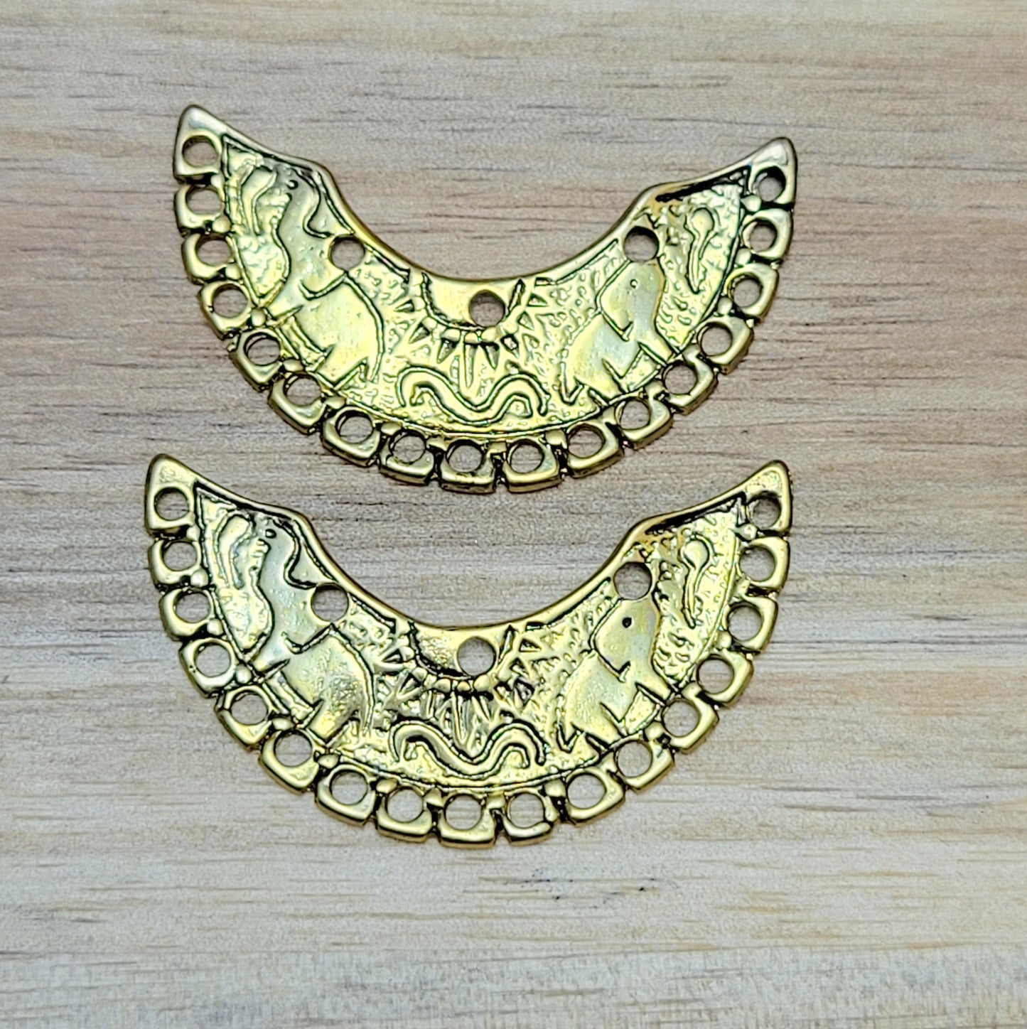 2 einzigartige, halbrunde Multiverbinder im Bollywood-Stil. Die ideale Schmuckkomponente für Tiaras, Fußschmuck, Handketten und Ohrschmuck im beliebt indischen Bollywood-Design. Die Verbinder sind antik silberfarbig und verfügen im inneren Bogen über 3 Löcher und am unteren Außenbogen befinden sich 17 Löcher. Auf dem Bogen selbst sind 2 Elefanten abgebildet sowie eine Sonne.