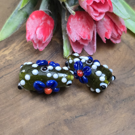 2 Handgemachte indische Glasperlen mit 3D-Blumenmuster in Tropfenform – Dunkelgrün/Blau/Weiß
Diese zauberhaften Glasperlen werden in sorgfältiger Handarbeit gefertigt und bestechen durch ihr opulentes 3D-Muster in Form von Dots und Blumen. Jede Perle ist ein Unikat und bringt einen Hauch traditioneller Handwerkskunst in deine Kreationen.