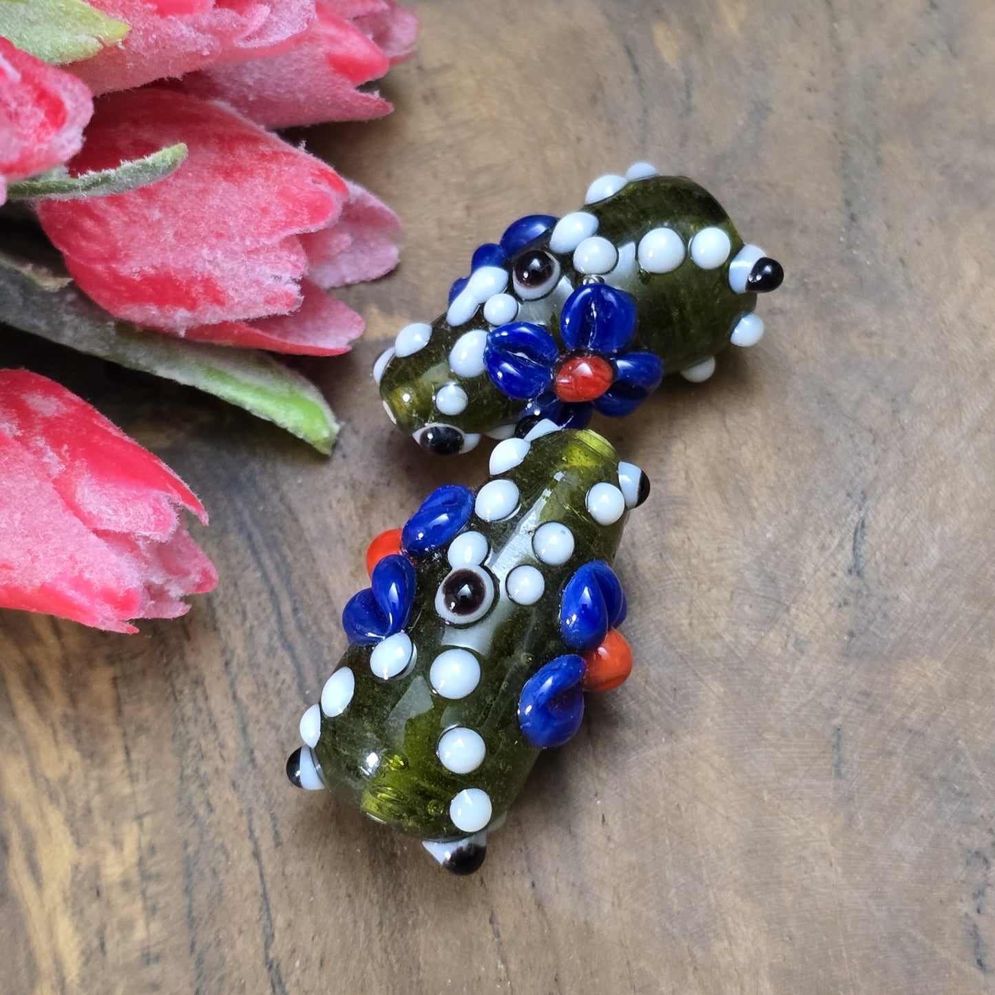 2 Handgemachte indische Glasperlen mit 3D-Blumenmuster in Tropfenform – Dunkelgrün/Blau/Weiß
Diese zauberhaften Glasperlen werden in sorgfältiger Handarbeit gefertigt und bestechen durch ihr opulentes 3D-Muster in Form von Dots und Blumen. Jede Perle ist ein Unikat und bringt einen Hauch traditioneller Handwerkskunst in deine Kreationen.
