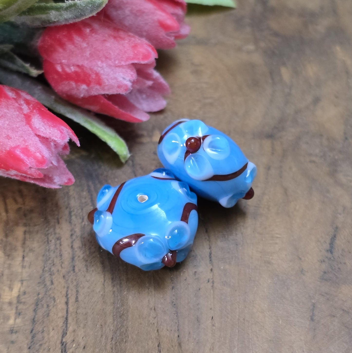 2 Handgemachte indische Glasperlen mit 3D-Blumenmuster – Blau/Rot/Weiß
Diese zauberhaften Glasperlen werden in sorgfältiger Handarbeit gefertigt und bestechen durch ihr filigranes 3D-Blumenmuster. Jede Perle ist ein Unikat und bringt einen Hauch traditioneller Handwerkskunst in deine Kreationen.