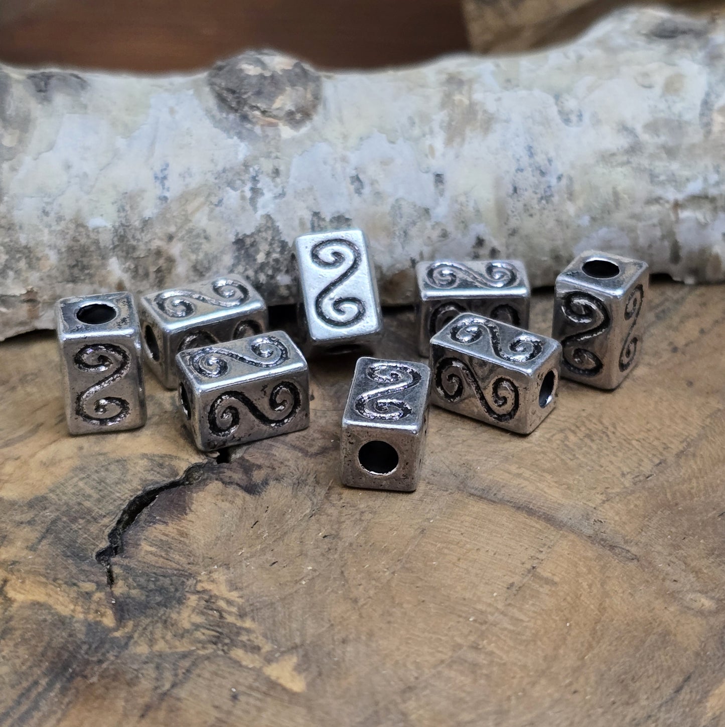 Eckige Metallperlen in Antiksilber mit S-förmigem Gravurmuster. Die strukturierte Oberfläche sorgt für einen eleganten Akzent. Mit einer Größe von 11 mm eignen sie sich perfekt für Armbänder, Ketten und kreative Schmuckdesigns.