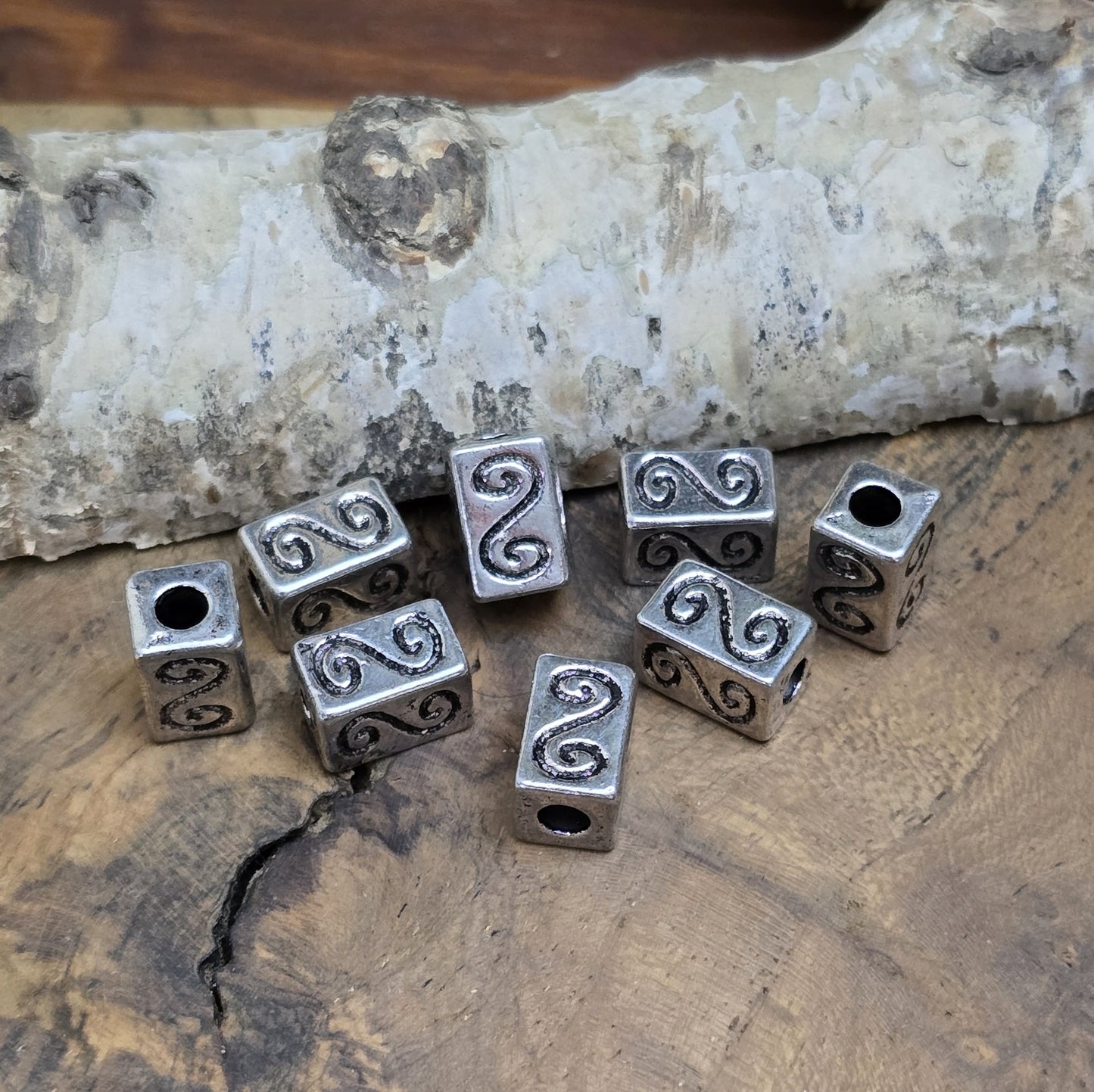 Eckige Metallperlen in Antiksilber mit S-förmigem Gravurmuster. Die strukturierte Oberfläche sorgt für einen eleganten Akzent. Mit einer Größe von 11 mm eignen sie sich perfekt für Armbänder, Ketten und kreative Schmuckdesigns.