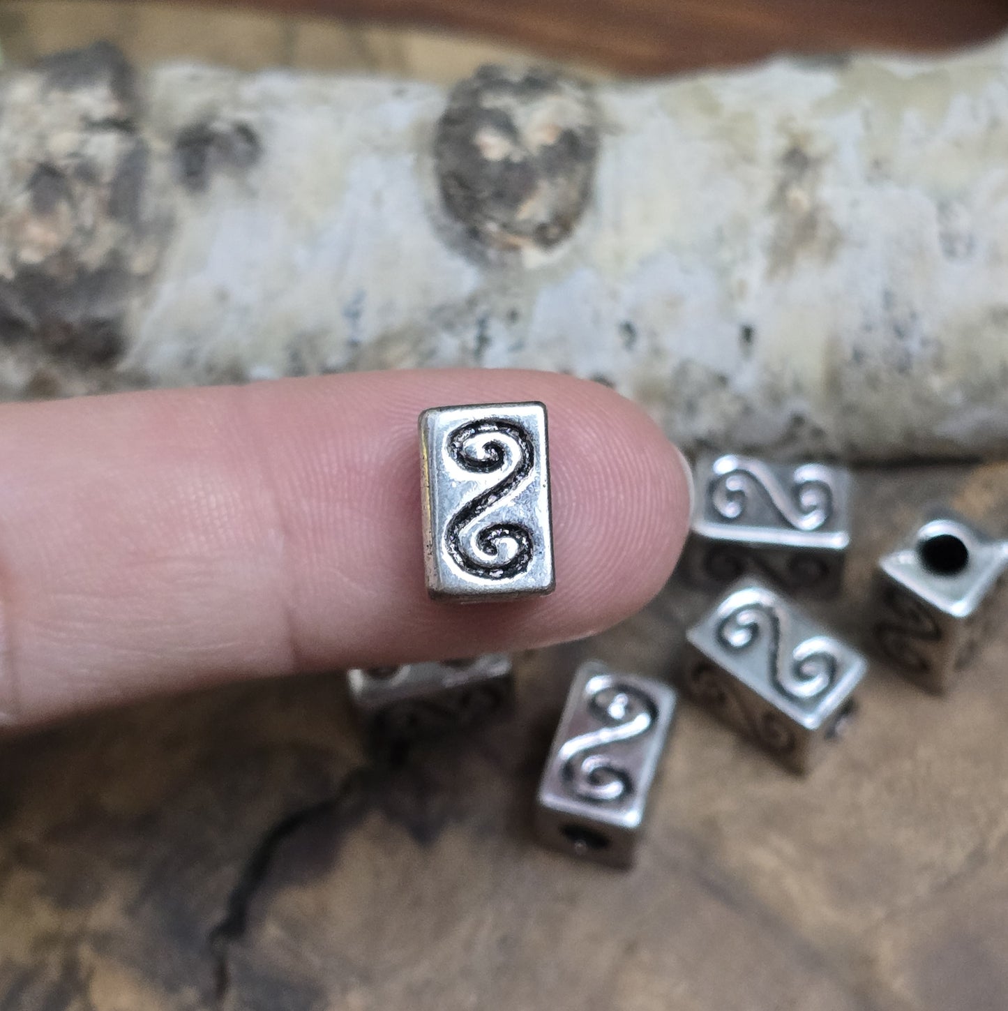 Eckige Metallperlen in Antiksilber mit S-förmigem Gravurmuster. Die strukturierte Oberfläche sorgt für einen eleganten Akzent. Mit einer Größe von 11 mm eignen sie sich perfekt für Armbänder, Ketten und kreative Schmuckdesigns.