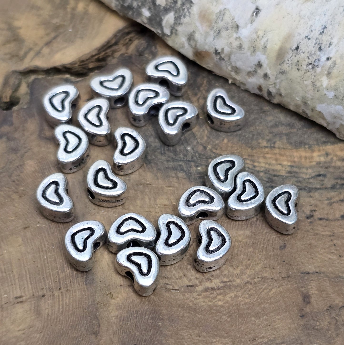 20 kleine Metallperlen in Herzform, antiksilberfarben, mit feinen Intarsien. Größe: 5 x 7 mm. Ideal für Schmuckprojekte wie Armbänder und Ketten. Das Fädelloch verläuft längs und erleichtert das Auffädeln auf verschiedene Drähte. Menge: 20 Stück.