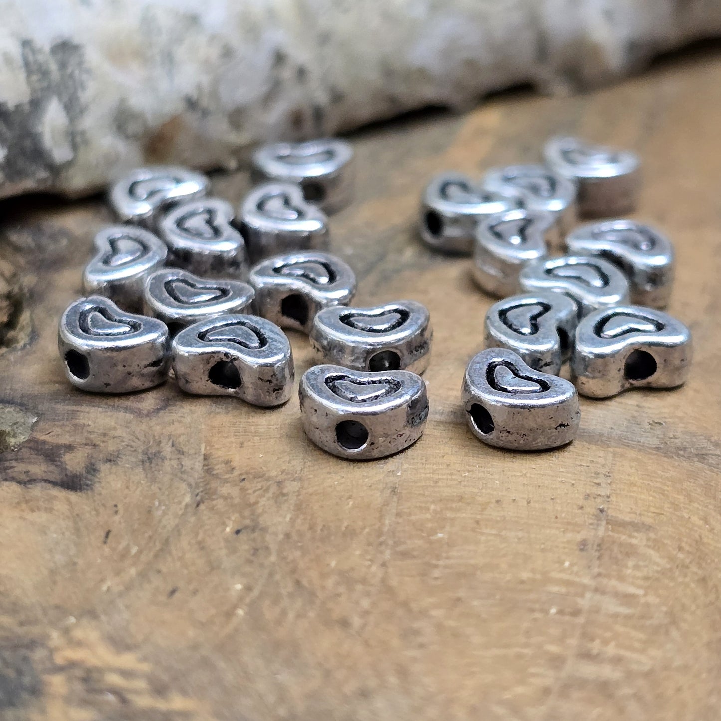 20 kleine Metallperlen in Herzform, antiksilberfarben, mit feinen Intarsien. Größe: 5 x 7 mm. Ideal für Schmuckprojekte wie Armbänder und Ketten. Das Fädelloch verläuft längs und erleichtert das Auffädeln auf verschiedene Drähte. Menge: 20 Stück.