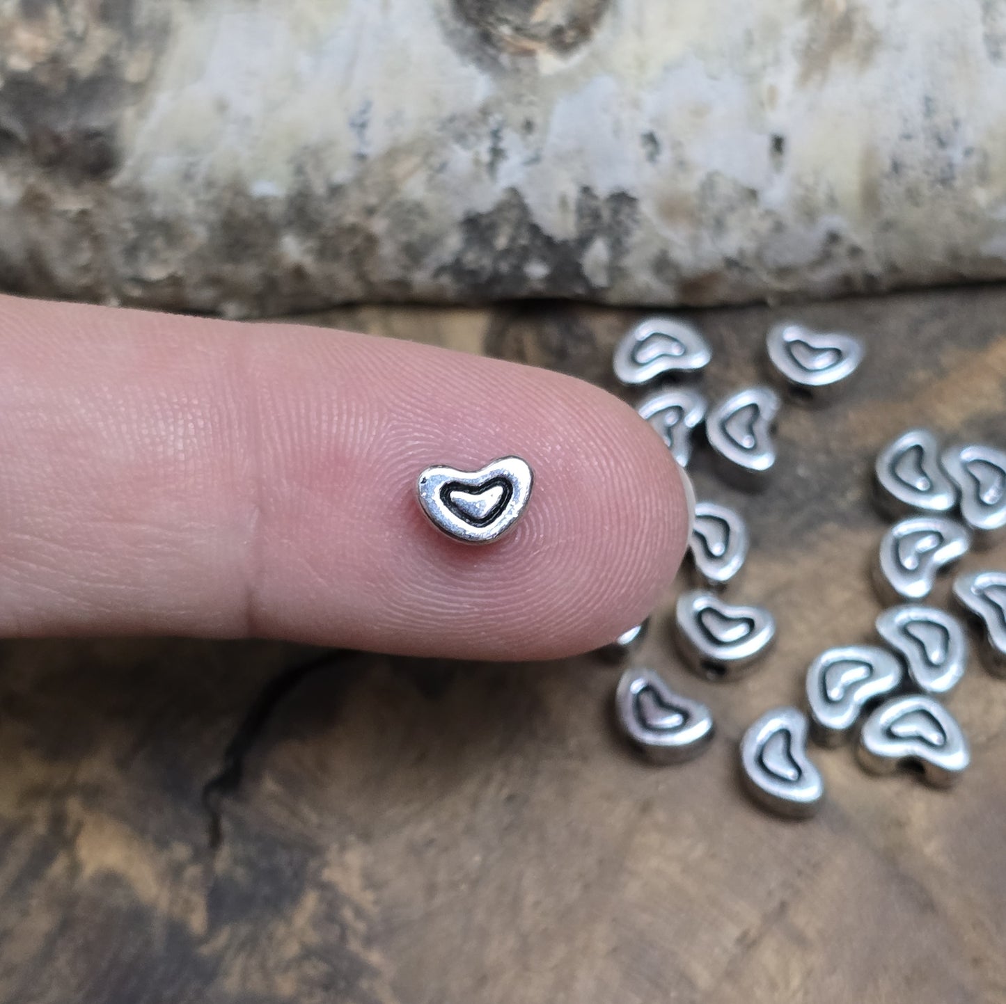 20 kleine Metallperlen in Herzform, antiksilberfarben, mit feinen Intarsien. Größe: 5 x 7 mm. Ideal für Schmuckprojekte wie Armbänder und Ketten. Das Fädelloch verläuft längs und erleichtert das Auffädeln auf verschiedene Drähte. Menge: 20 Stück.