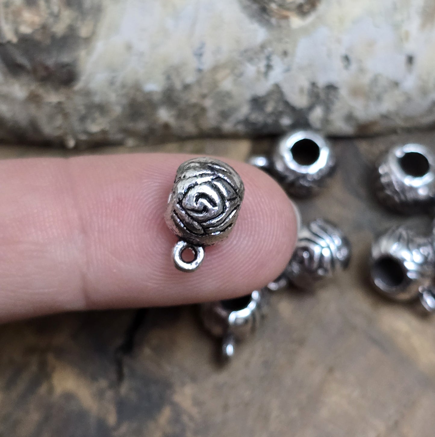 10 runde Metallperlen in Antiksilber mit Rosenmotiv und großer Öse. Größe: 8 x 12 mm, Fädelloch: 4 mm. Perfekt für Armbänder, Ketten und zum Befestigen kleiner Anhänger. Ideal für romantische Schmuckdesigns und traditionelle Kreationen.