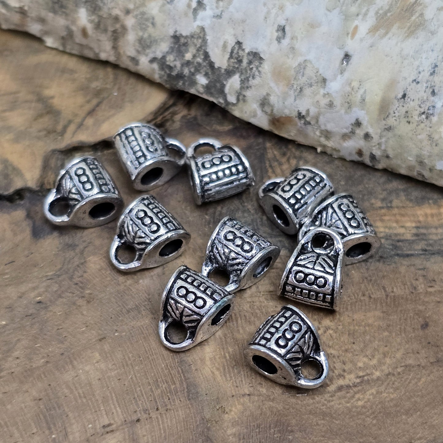 10 Metallperlen mit Öse, antiksilberfarben, 7 x 9 mm. Jede Perle ist mit einem feinen Ethnomuster verziert. Das große Fädelloch (ca. 3 mm) ermöglicht einfaches Auffädeln. Mit der Öse können Anhänger befestigt werden. Perfekt für Armbänder, Ketten und kreative Designs.