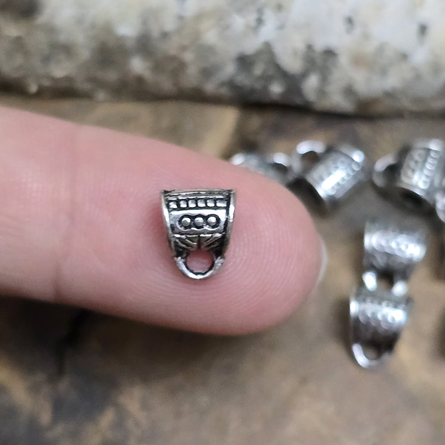 10 Metallperlen mit Öse, antiksilberfarben, 7 x 9 mm. Jede Perle ist mit einem feinen Ethnomuster verziert. Das große Fädelloch (ca. 3 mm) ermöglicht einfaches Auffädeln. Mit der Öse können Anhänger befestigt werden. Perfekt für Armbänder, Ketten und kreative Designs.