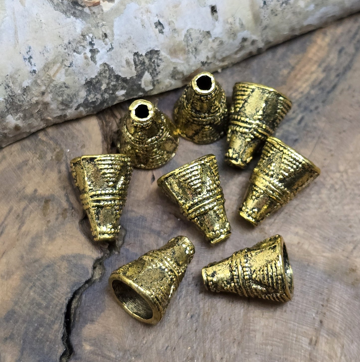 4 konische Kappen aus Metall, Ethnodesign, 11x8mm, antik goldfarbig
Diese konischen Kappen aus Metall bieten einen stilvollen Abschluss für Perlen, Ketten oder Armbänder. Sie sind auch ideal, um Perlen vor dem Anstoßen zu schützen und verleihen deinem Schmuck oder Accessoire eine geheimnisvolle Note.