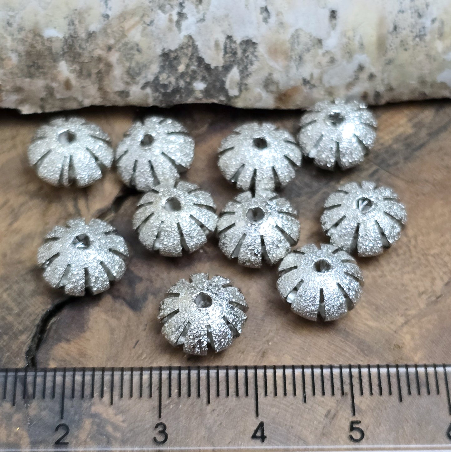 10 silberfarbene Stardust-Metallperlen, 10 x 6 mm, in UFO-Form mit glitzernder Oberfläche und gefächertem Rand. Ideal für Schmuckprojekte wie Armbänder, Ketten oder Ohrringe. Fädelloch: 1,6 mm. Perfekt für edle und stilvolle Akzente.
