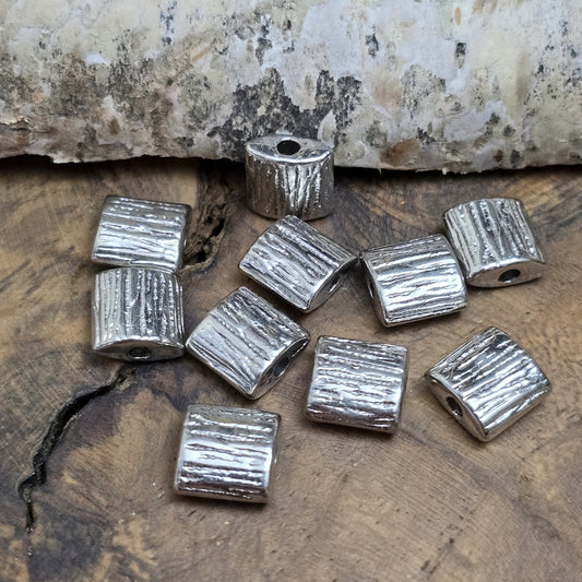 10 antiksilberfarbene Metallperlen in Kissenform, 8 x 8 mm, mit strukturierter Oberfläche. Ideal für Schmuckdesigns wie Ketten, Armbänder oder kreative Dekorationen. Sie setzen stilvolle Akzente in jedem Projekt.