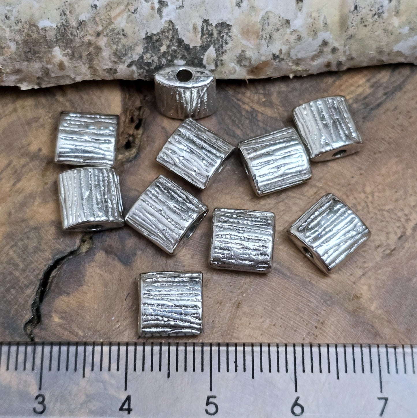 10 antiksilberfarbene Metallperlen in Kissenform, 8 x 8 mm, mit strukturierter Oberfläche. Ideal für Schmuckdesigns wie Ketten, Armbänder oder kreative Dekorationen. Sie setzen stilvolle Akzente in jedem Projekt.