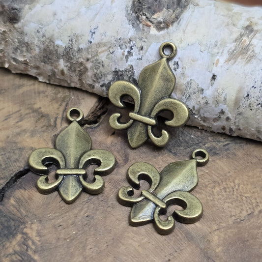 Das Bild zeigt 3 Anhänger Fleur de Lys 22mm, antik bronzefarbig. Ideal für die individuelle Schmuckfertigung.