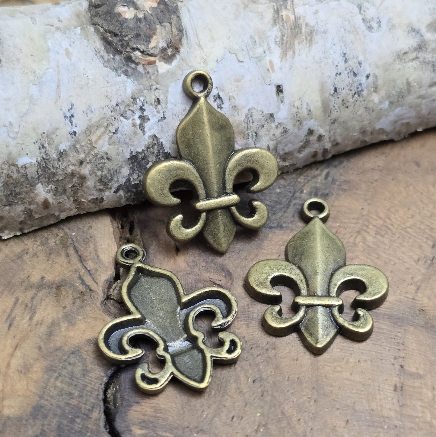 Das Bild zeigt 3 Anhänger Fleur de Lys 22mm, antik bronzefarbig. Ideal für die individuelle Schmuckfertigung.