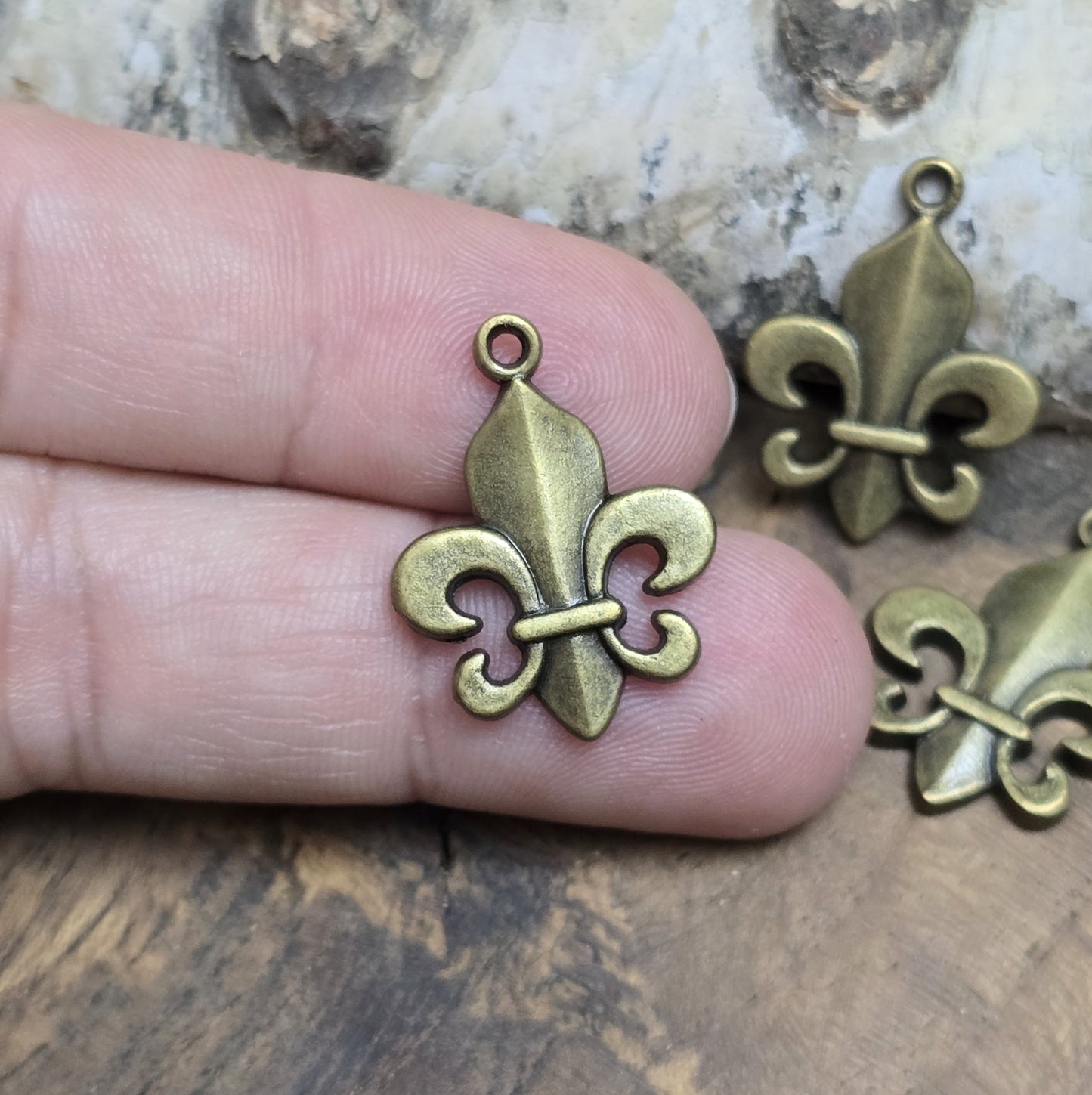 Das Bild zeigt 3 Anhänger Fleur de Lys 22mm, antik bronzefarbig. Ideal für die individuelle Schmuckfertigung.