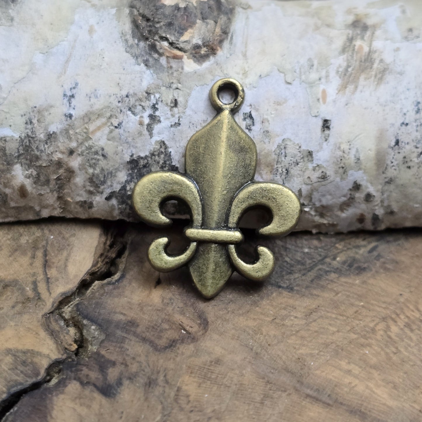 Das Bild zeigt 3 Anhänger Fleur de Lys 22mm, antik bronzefarbig. Ideal für die individuelle Schmuckfertigung.