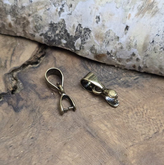 Das Bild zeigt 2 Collierschlaufen mit Dorn antik bronzefarbig - 5 x 4mm
Diese Collierschlaufen sind ideal, um flache Schmucksteine mit oberer Bohrung in Anhänger zu verwandeln.