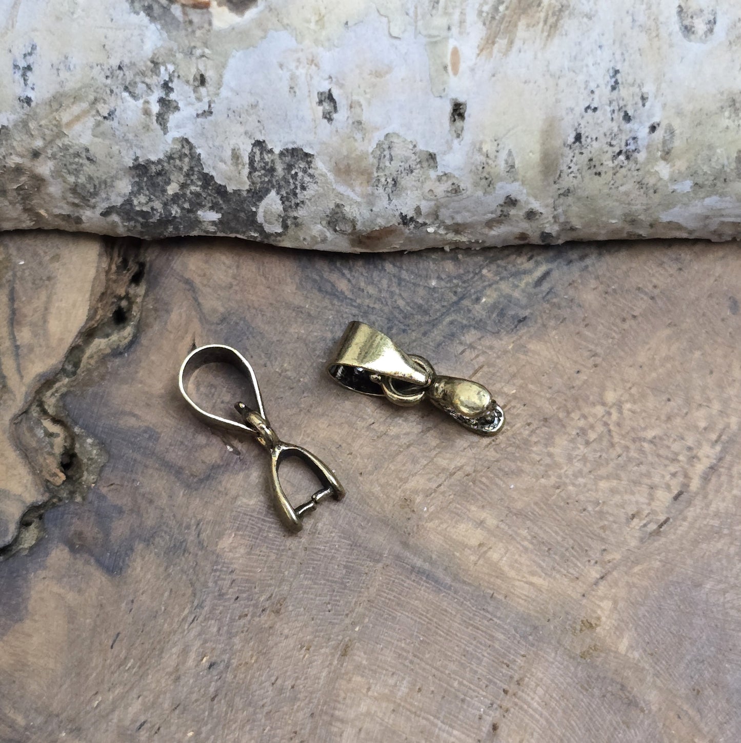Das Bild zeigt 2 Collierschlaufen mit Dorn antik bronzefarbig - 5 x 4mm
Diese Collierschlaufen sind ideal, um flache Schmucksteine mit oberer Bohrung in Anhänger zu verwandeln.