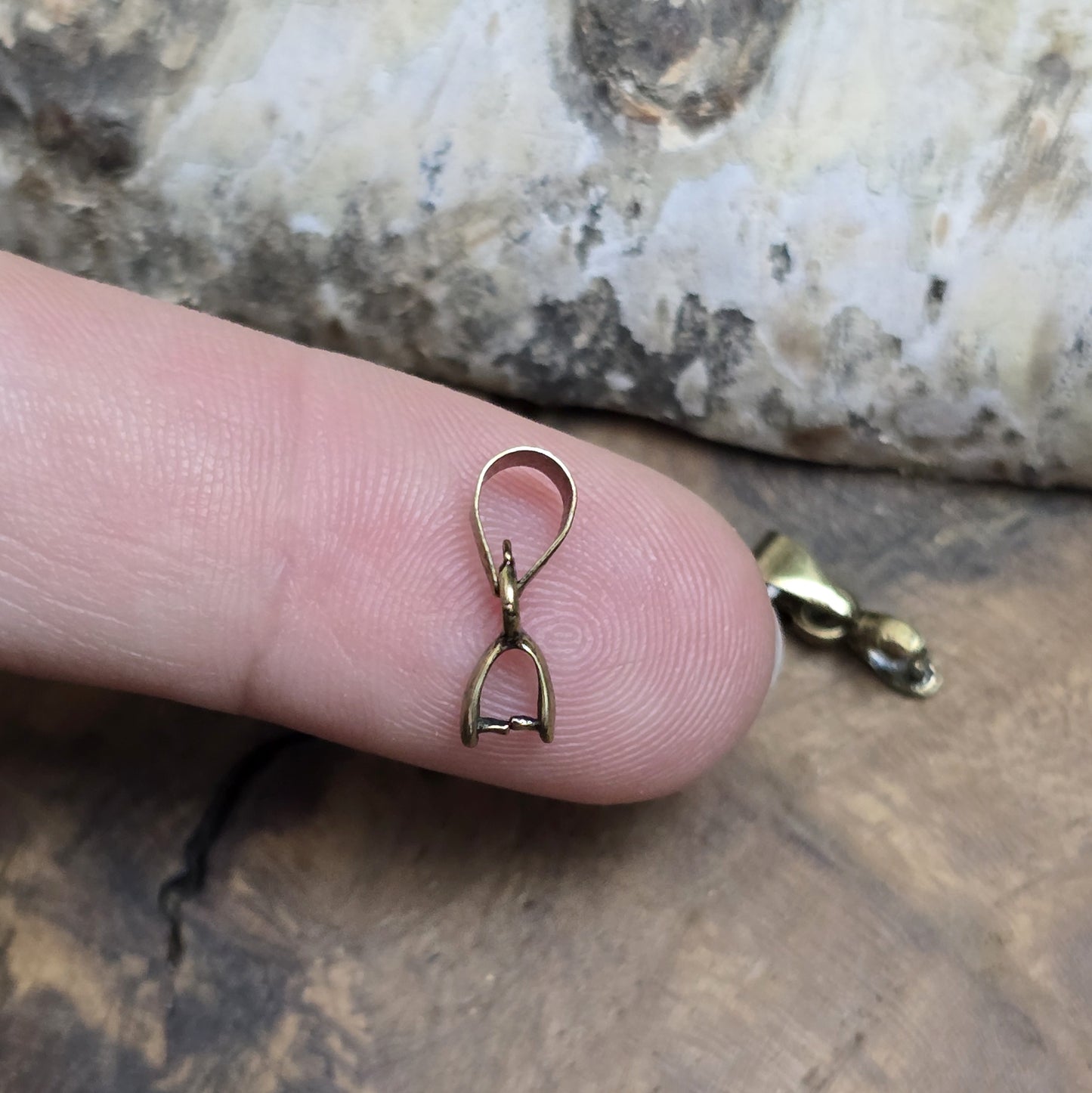 Das Bild zeigt 2 Collierschlaufen mit Dorn antik bronzefarbig - 5 x 4mm
Diese Collierschlaufen sind ideal, um flache Schmucksteine mit oberer Bohrung in Anhänger zu verwandeln.