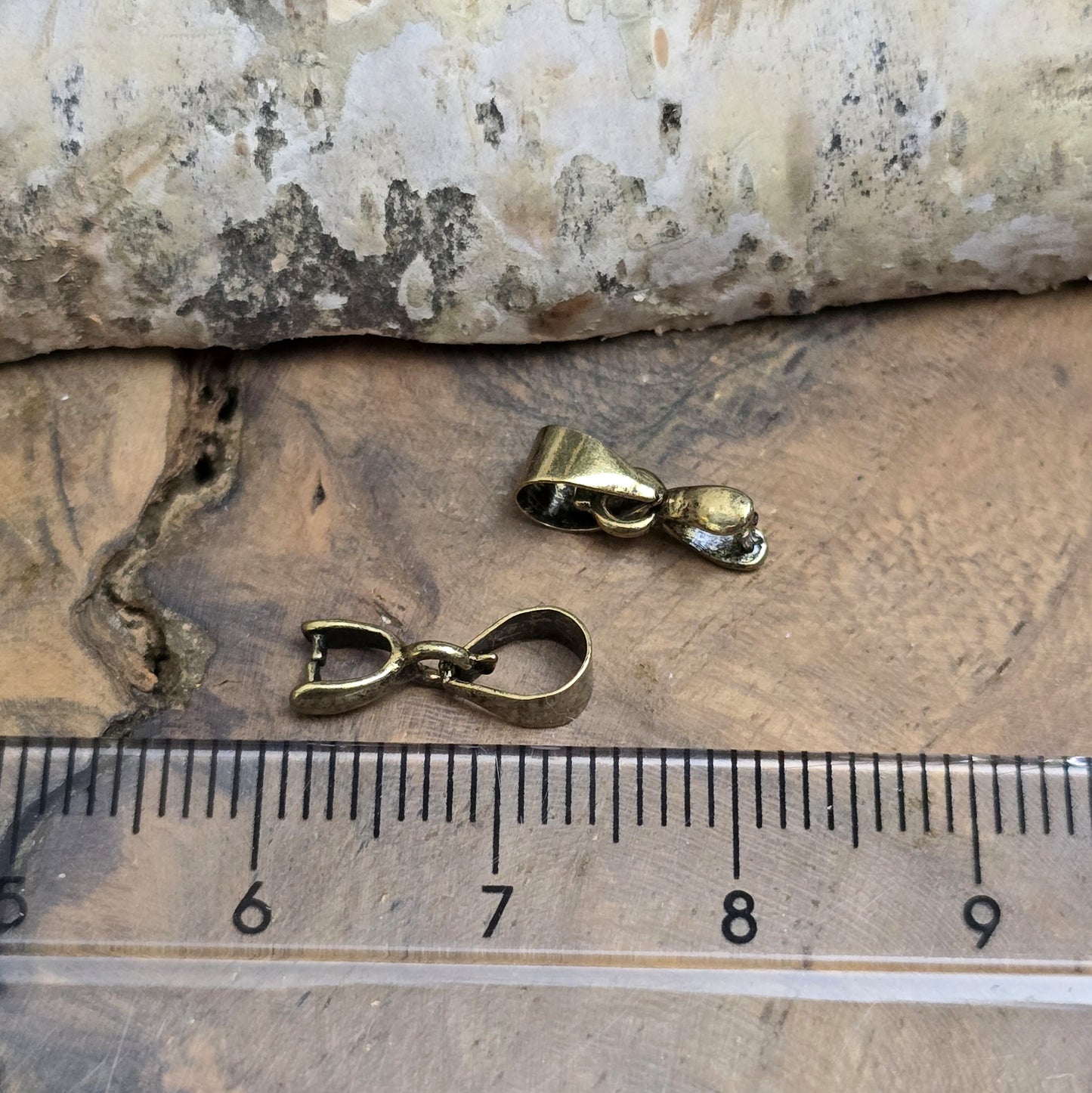 Das Bild zeigt 2 Collierschlaufen mit Dorn antik bronzefarbig - 5 x 4mm
Diese Collierschlaufen sind ideal, um flache Schmucksteine mit oberer Bohrung in Anhänger zu verwandeln.