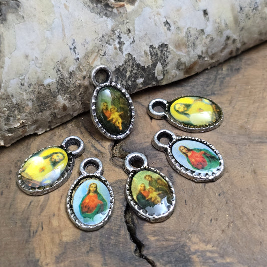Das Bild zeigt kleine Anhänger mit Bild von Jesus - Silberfarbig 9mm
Diese kleinen Anhänger zeigen ein Bildnis von Jesus. Das Bild ist versiegelt mit Kunstharz um es vor Beschädigungen zu schützen. Auf der Rückseite befindet sich ein Kreuz. Ideal für Armbänder, Ohrschmuck und andere kreative Anwendungen. 