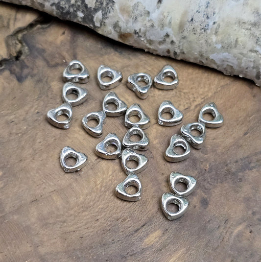 Das Bild zeigt dekorative Herzperlen mit antikem Finish, sie bringen einen charmanten und eleganten Touch in deine Schmuckkreationen. Perfekt als Abstandhalter oder zur Betonung dezent stilvoller Details.