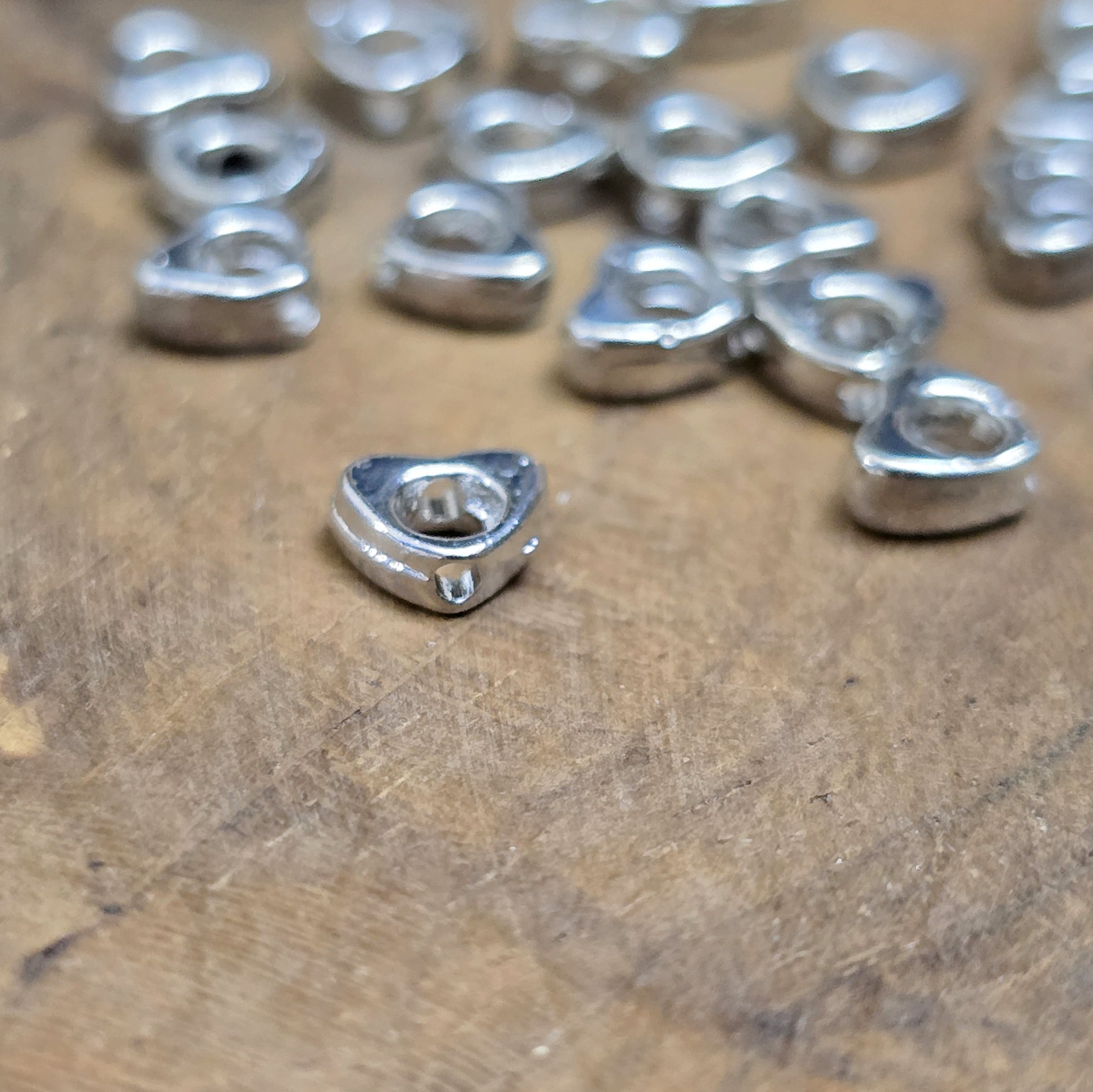Das Bild zeigt dekorative Herzperlen mit antikem Finish, sie bringen einen charmanten und eleganten Touch in deine Schmuckkreationen. Perfekt als Abstandhalter oder zur Betonung dezent stilvoller Details.