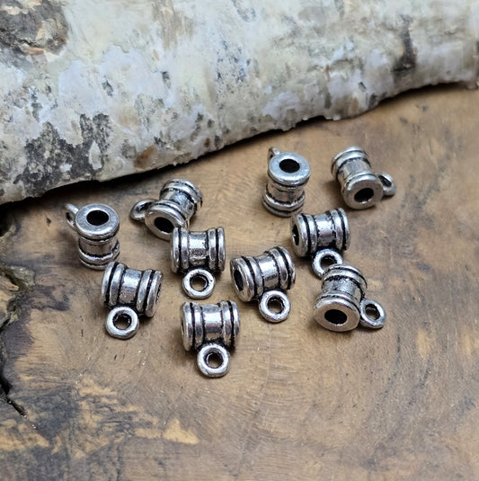 Das Bild zeigt antiksilberfarbene Metallperlen mit Öse. Sie sind eine ideale Ergänzung für kreative Schmuckprojekte. Dank des großzügigen 2,5-mm-Lochs lassen sie sich mühelos auf verschiedene Bänder und Kordeln auffädeln. Die zusätzliche Öse eröffnet zahlreiche Designmöglichkeiten, um Schmuckstücke individuell zu gestalten.