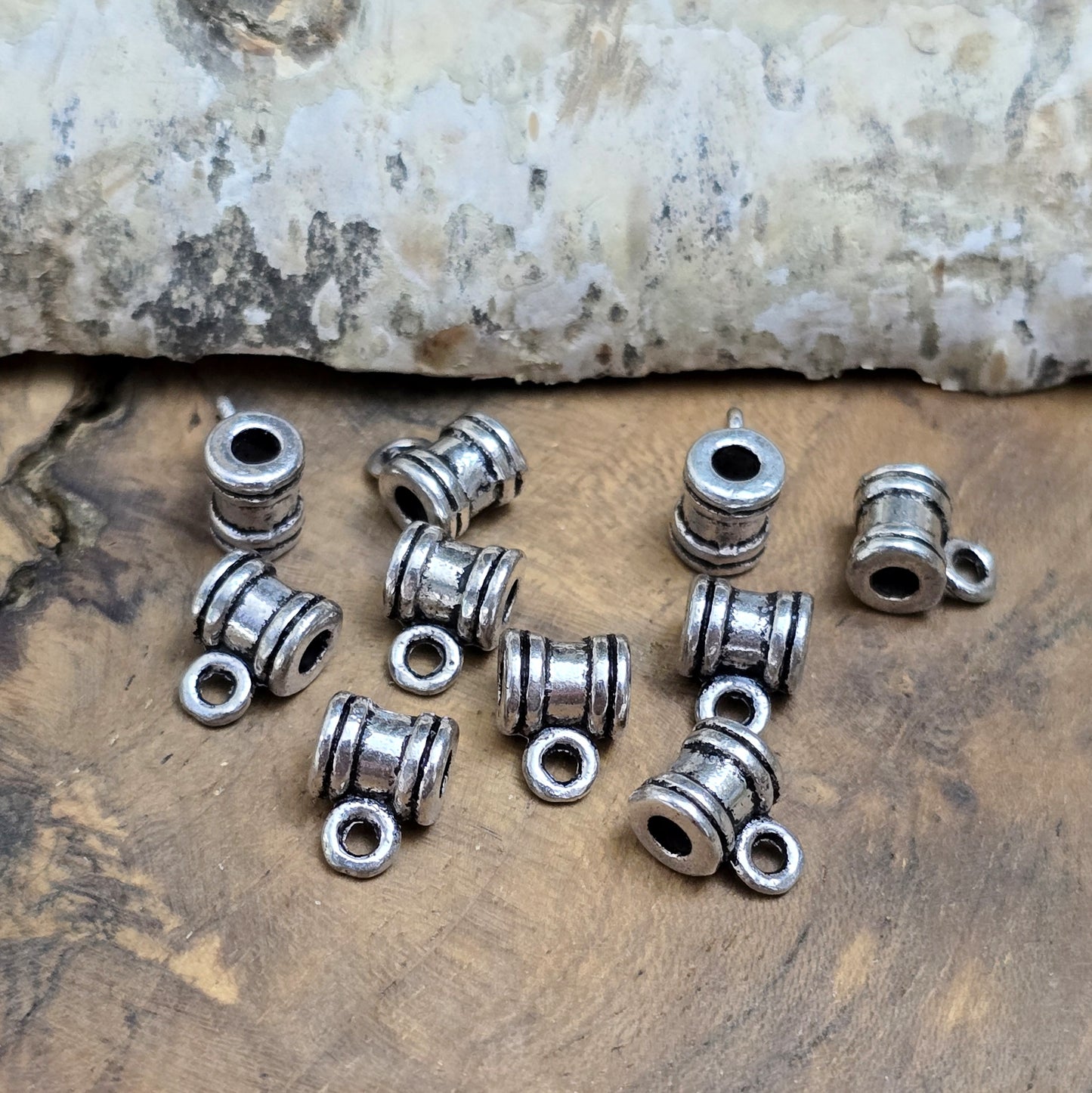 Das Bild zeigt antiksilberfarbene Metallperlen mit Öse. Sie sind eine ideale Ergänzung für kreative Schmuckprojekte. Dank des großzügigen 2,5-mm-Lochs lassen sie sich mühelos auf verschiedene Bänder und Kordeln auffädeln. Die zusätzliche Öse eröffnet zahlreiche Designmöglichkeiten, um Schmuckstücke individuell zu gestalten.