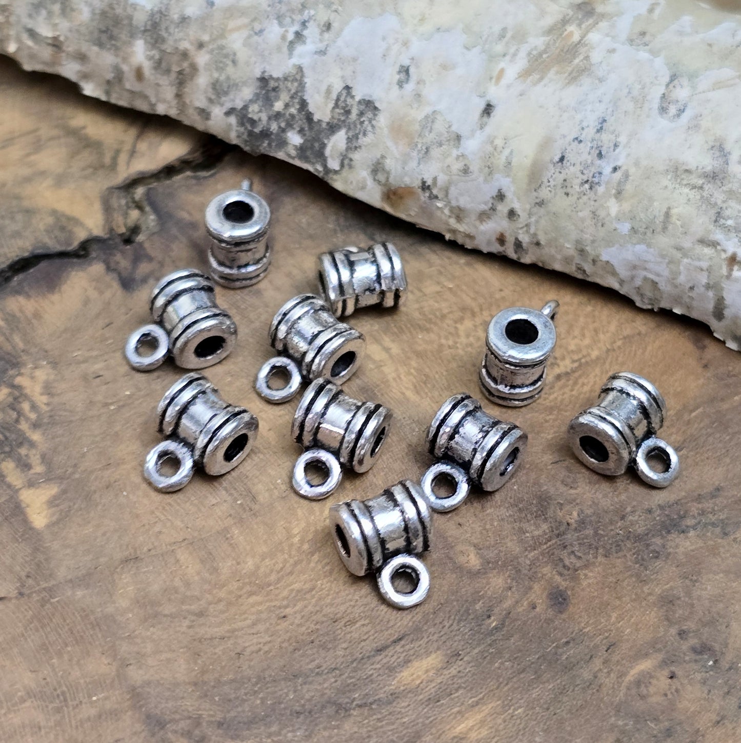 Das Bild zeigt antiksilberfarbene Metallperlen mit Öse. Sie sind eine ideale Ergänzung für kreative Schmuckprojekte. Dank des großzügigen 2,5-mm-Lochs lassen sie sich mühelos auf verschiedene Bänder und Kordeln auffädeln. Die zusätzliche Öse eröffnet zahlreiche Designmöglichkeiten, um Schmuckstücke individuell zu gestalten.
