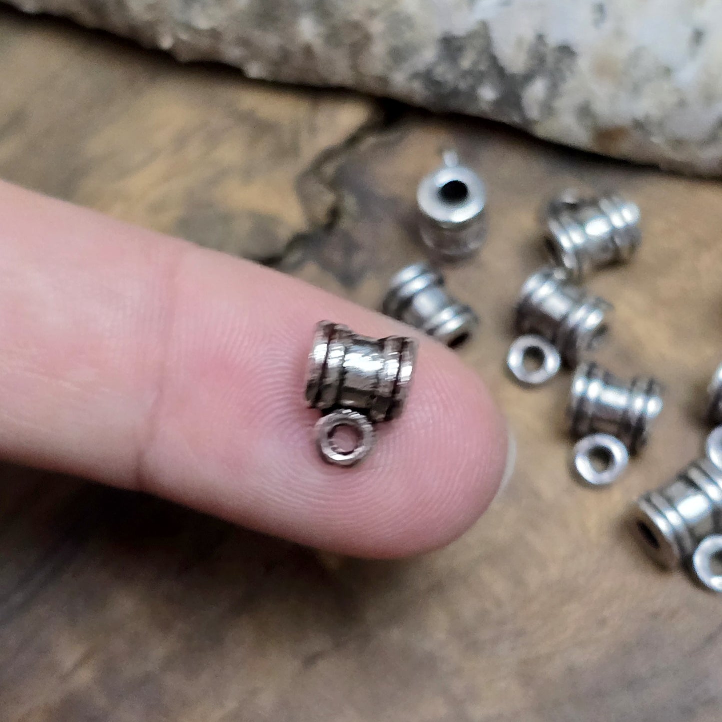 Das Bild zeigt antiksilberfarbene Metallperlen mit Öse. Sie sind eine ideale Ergänzung für kreative Schmuckprojekte. Dank des großzügigen 2,5-mm-Lochs lassen sie sich mühelos auf verschiedene Bänder und Kordeln auffädeln. Die zusätzliche Öse eröffnet zahlreiche Designmöglichkeiten, um Schmuckstücke individuell zu gestalten.