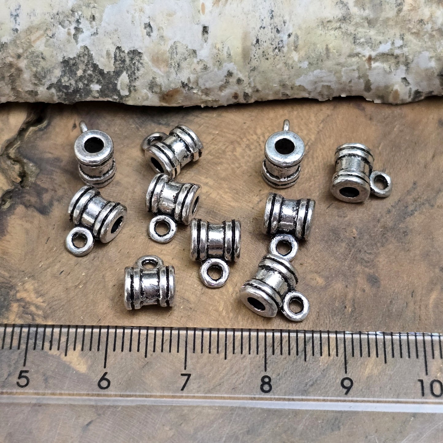 Das Bild zeigt antiksilberfarbene Metallperlen mit Öse. Sie sind eine ideale Ergänzung für kreative Schmuckprojekte. Dank des großzügigen 2,5-mm-Lochs lassen sie sich mühelos auf verschiedene Bänder und Kordeln auffädeln. Die zusätzliche Öse eröffnet zahlreiche Designmöglichkeiten, um Schmuckstücke individuell zu gestalten.