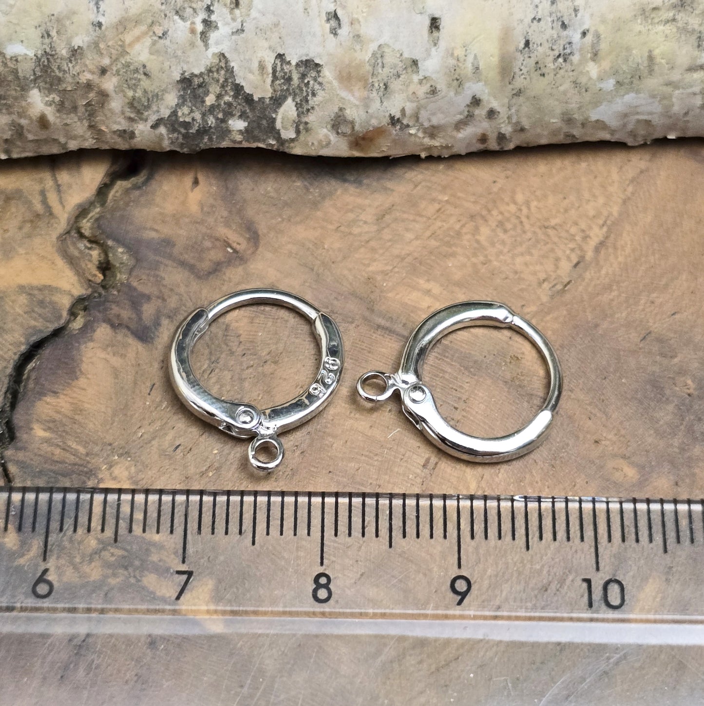 Das Bild zeigt Creolen mit Anhängeröse. Sie sind exquisite Schmuckstücke, die aus 925er Silber gefertigt sind. Mit einem Durchmesser von 13 mm (außen) sind sie elegant und perfekt für den täglichen Gebrauch oder besondere Anlässe.