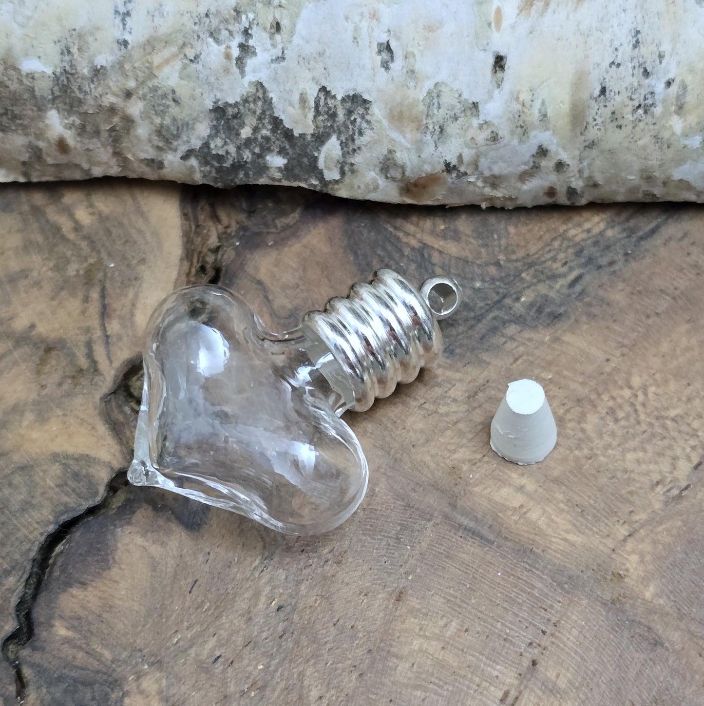 Kleiner Phiolenanhänger aus Glas, in Form eines Herzens mit silberfarbiger Kappe. Ideal zum Befüllen mit beschriftetem Reiskorn, Sand, Milchzahn, Asche, Haare udg.