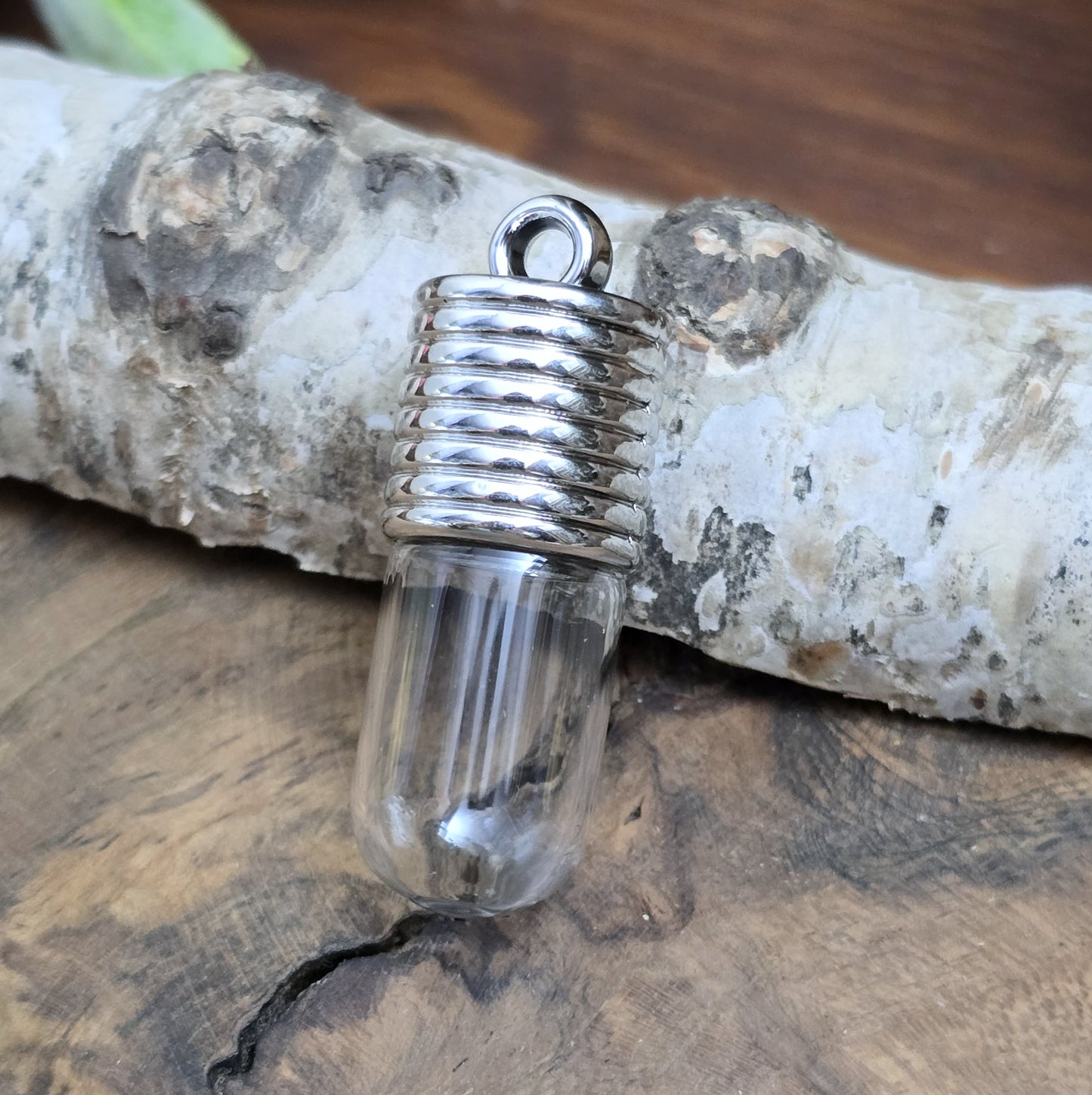 Anhänger Glasflasche mit rundem Boden zum selber befüllen. Die Glasflasche hat oben eine "große" Öffnung und bietet Platz für eine Vielzahl von Erinnerungen und Materialien wie Edelsteinsplitter, Sand, Glitzer, Granulat, Tierhaare, Milchzähne, kleine Turmdeckelschnecken etc. (bitte beachten Sie die Öffnungsgröße).