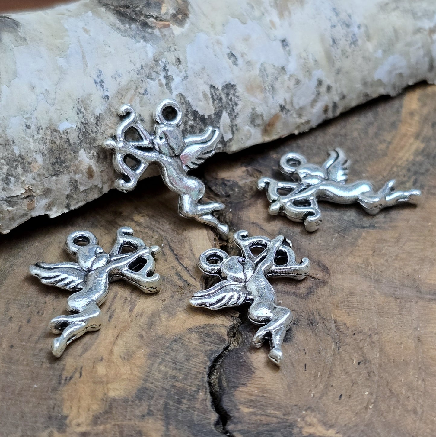 4 Charms Armor in antik silberfarbig liegend auf einem Brett aus Holz