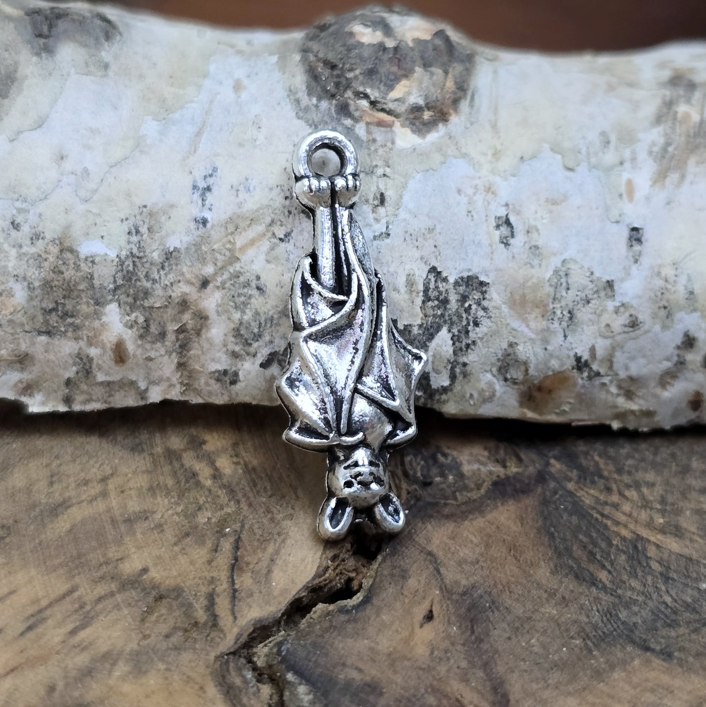 Einzelner antik silberner Charm, hängende Fledermaus in Nahaufnahme.