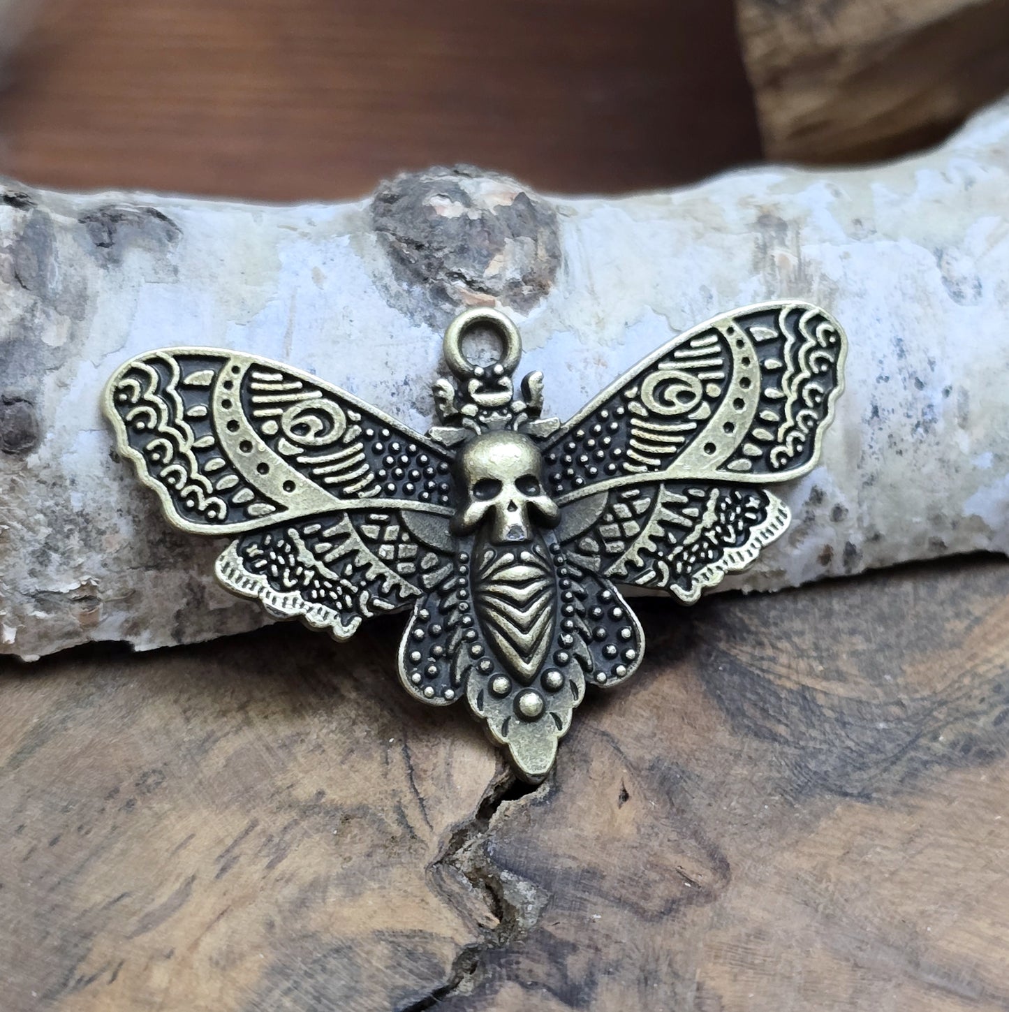 Das Bild zeigt einen Anhänger im antik bronzefarbenen Look. Mit einer Breite von 27 mm und einer stabilen Öse eignet er sich perfekt für die Gestaltung von Ketten, Chokern oder anderen individuellen Schmuckstücken.
