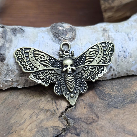 Das Bild zeigt einen Anhänger im antik bronzefarbenen Look. Mit einer Breite von 27 mm und einer stabilen Öse eignet er sich perfekt für die Gestaltung von Ketten, Chokern oder anderen individuellen Schmuckstücken.