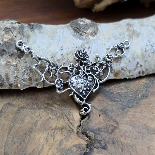 Das Bild zeigt eine Schmuckkomponente für Ketten, Choker und Armbänder. Der Verbinder ist antik silberfarbig und kann z.B. durch colorieren zu einem ganz persönlichen Schmuckteil werden. In der Mitte befindet sich ein Herz, umgeben von Rosen.